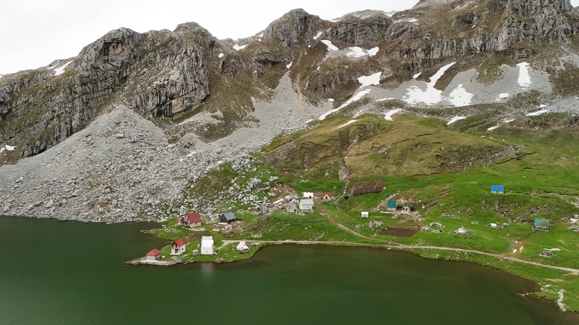 Katun uz planinsko jezero pod stijenama